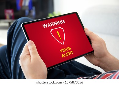 man hands holding computer tablet with warning virus alert on the screen in the house room - Powered by Shutterstock