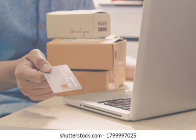 Man hands are holding a credit card and a box parcel hematite and laptop at the table.Online delivery service business concept. - Shutterstock ID 1799997025