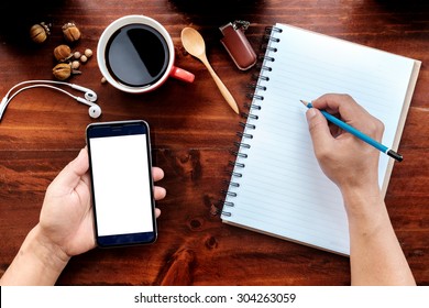 A Man Hands Holding Empty Screen Of Smartphone On Wood Desk Work. Top View Shot.