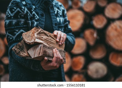 Man Hands Holding Firewood. Unrecognizable male caring wood logs to the house, to start a fireplace. Rustic countryside background, still life. slow living.