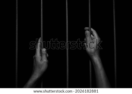 Man Hands holding iron bars in jail. Imprisoned criminal concept.
