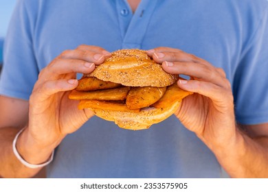 Man hands holding Pane e panelle - chickpea flour fritters in mafalda bread roll, sandwiche, a typical street food of Palermo, Sicily, Italy. Easy and delicious vegan food.