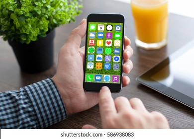 man hands holding phone with home screen icons apps in office