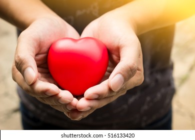Man hands, holding red heart, giving to someone