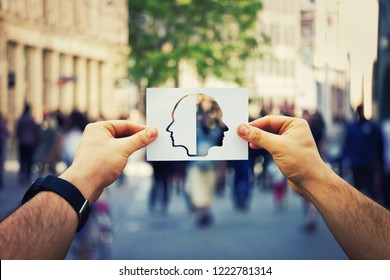 Man hands holding a white paper sheet with two faced head over a crowded street background. Split personality, bipolar mental health disorder concept. Schizophrenia psychiatric disease. - Shutterstock ID 1222781314