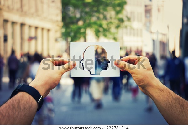 Man\
hands holding a white paper sheet with two faced head over a\
crowded street background. Split personality, bipolar mental health\
disorder concept. Schizophrenia psychiatric\
disease.