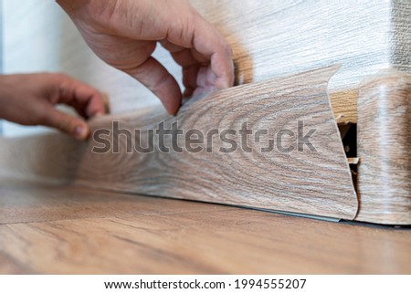 Man hands intall floor plastic skirting boards. replacement of the plastic skirting board on the floor. selective focus on the skirting board