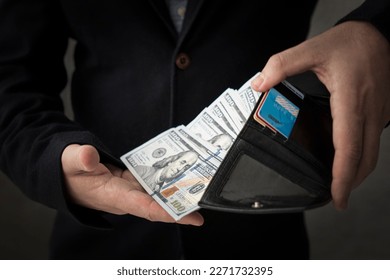 Man hands with leather wallet. Right hand is pulling American money - US Dollars. getting a salary, a lot of money in wallet. - Shutterstock ID 2271732395