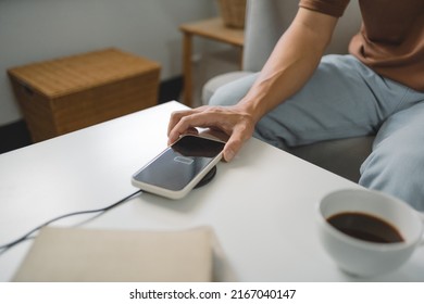 Man hands plugging a charger in a smart phone. Charging Smartphone with Wireless Charging Pad at Home