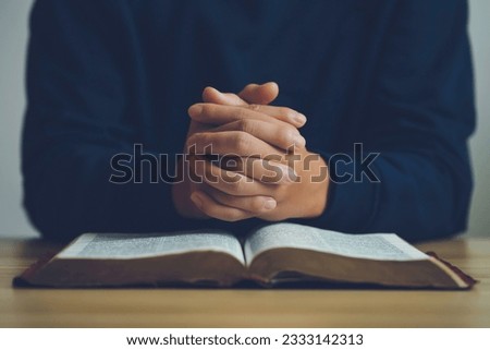 Man hands praying to god on the open bible on a wooden table. begging for forgiveness and believing in goodness. Pray for god blessing to wish to have a better life and life to be out of the crisis