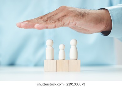 The Man Hands Protect Over Wooden Figure. Planning, Saving Family, Quality Family, Hedging, Stability In Life,health Care And Insurance, Family Mental Health, International Day Of Families