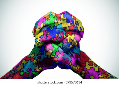 man hands put together patterned with many puzzle pieces of different colors, symbol of the autism awareness, with a slight vignette added