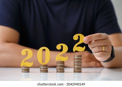  Man Hands Putting Gold Wooden Number 2022 On Stack Of Coins. Tax Payment, Investment And Banking.2022 New Year Saving Money And Financial Planning Concept.