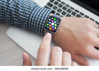 Man hands and smart touch watch with home screen icons apps background laptop