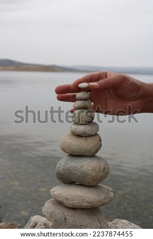 man hands stacked pebble stones tower on sea beach relaxing harmony summer travel vacation. male arms pillar formation peaceful balance pyramid spa spiritual gravel cobblestone at seaside.