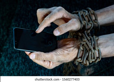 man hands tied with metallic chain with padlock on dark background suggesting internet or social media addiction. Hold in dirty hands.