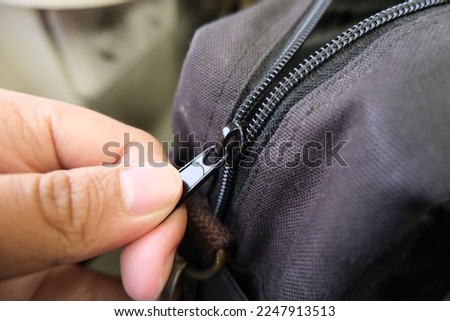 Man hands unzipping a black bag.