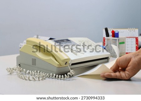 Man hands using a fax machine, putting paper in and sending fax in office