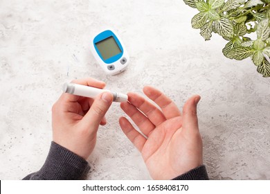 Man Hands Using Lancet On Finger To Check Blood Sugar Or Ketones Level By Glucose Meter. Medicine Diabetes Keto Diet Health Care At Home