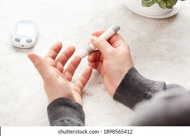 man hands using lancet on finger to check blood sugar or ketones level by glucose meter. medicine diabetes keto diet health care at home