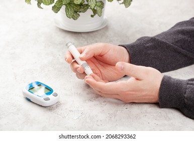 Man Hands Using Lancet On Finger To Check Blood Sugar Or Ketones Level By Glucose Meter. Medicine Diabetes Keto Diet Health Care At Home