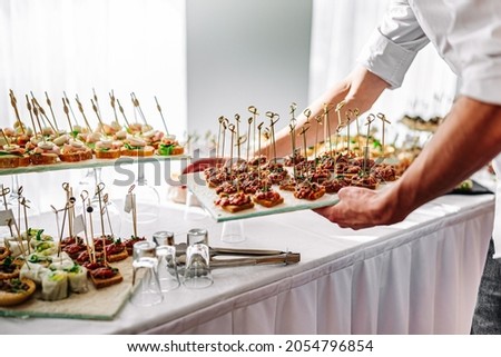 man  hands of a waiter prepare food for a buffet table in a restaurant