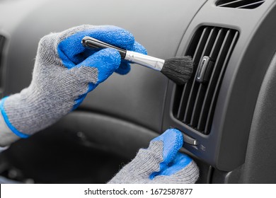 Man Hands Wearing Protective Gloves Using Cleaning Brush And Removing Dust From Car Air Conditioning Vent Grill. Car Detailing Or Valeting Concept.