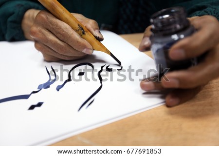man hands writing arabic calligraphy with ink