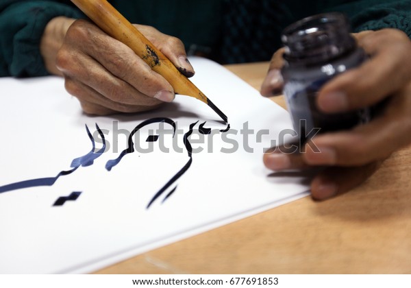 man hands
writing arabic calligraphy with
ink