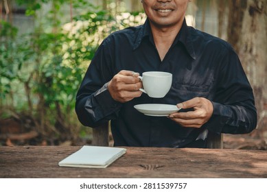 Man hands writing notebook diary with coffee cup and smartphone on wood desk. Close up man hands using pen sitting at wooden table outdoors lifestyle. Men write planner note diary office agenda