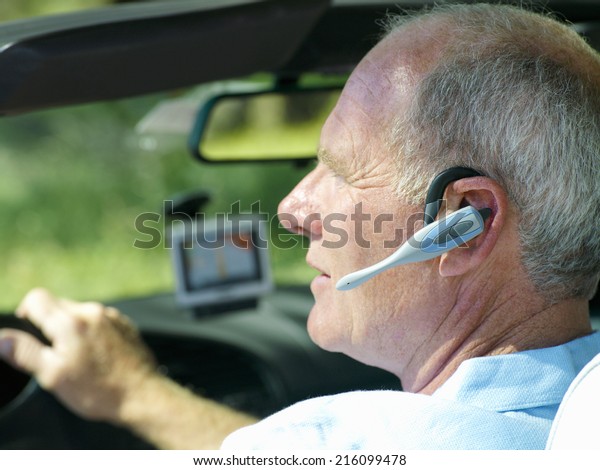 Man with\
hands-free device in car, side\
view