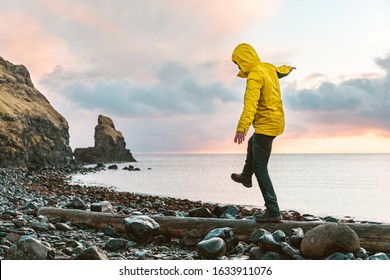 Man hanging in the balance over a log at seaside in Scotland - Hiker having fun at beautiful destination Talisker bay after the rain - Filter applied, travel and adventure concepts