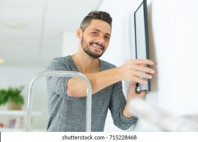 Man Hanging Blank Picture Frame On Wall