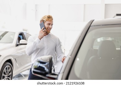 Man happy customer male buyer client wear white shirt talk by mobile cell phone advise choose auto want buy new car automobile in showroom vehicle dealership store motor show indoor. Sales concept. - Powered by Shutterstock