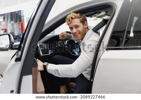 Man happy customer male buyer client in shirt get out car touch door look camera salon drive choose auto want buy new automobile in showroom vehicle dealership store motor show indoor Sales concept
