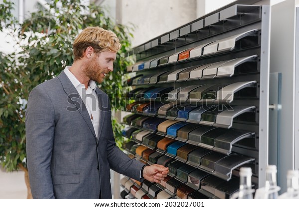 Man happy customer male buyer client in classic\
suit look at color paint palette chooses auto want buy new\
automobile in car showroom vehicle salon dealership store motor\
show indoor Sales concept.