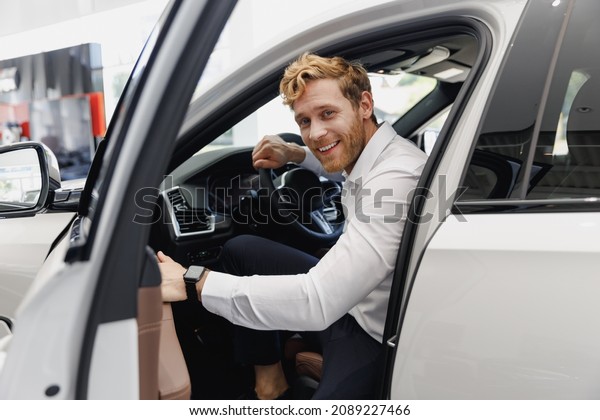 Man happy customer male buyer client in shirt get\
out car touch door look camera salon drive choose auto want buy new\
automobile in showroom vehicle dealership store motor show indoor\
Sales concept