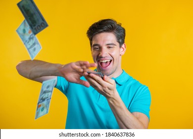 Man with a happy face scatters money. People overspend US currency. The man is flush with dollars on yellow studio background.