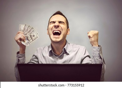 man is happy in front of the computer to hold 500 dollars. Winning in an online casino. Profit from online stock trading. Easy money. Earnings on the Internet.