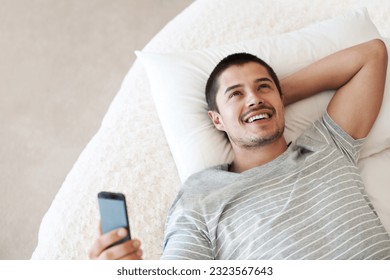 Man, happy and thinking with a phone on a bed for communication, chat or notification at home. Happy young person with a smartphone for message idea with internet connection, app and social media - Powered by Shutterstock