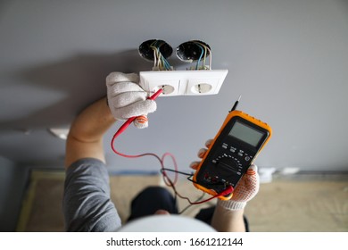 Man In Hard Hat And Protective Gloves Checking Wal Outlet With Tester Closeup