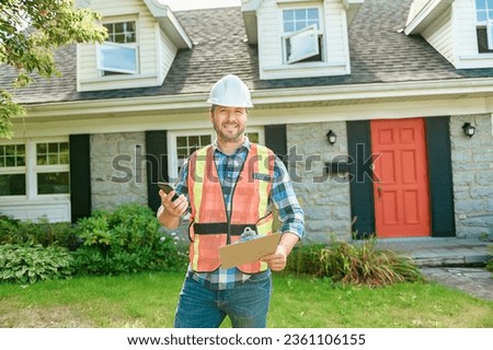 A man with hard hat standing in front of a house to inspect