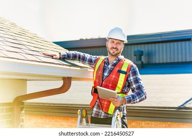 A man with hard hat standing on steps inspecting house roof - Powered by Shutterstock