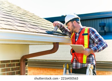A man with hard hat standing on steps inspecting house roof - Shutterstock ID 2216450563