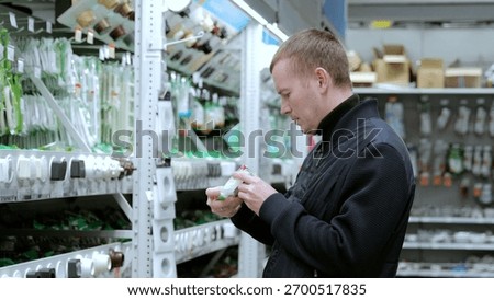A man in a hardware store, choosing electrical wires. Electrician carefully examines the packaging of an electrical product to choose the best option for his project