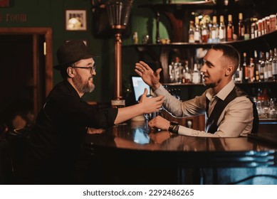 man has fun chatting with a bartender at bar counter with a glass of beer in a pub - Powered by Shutterstock