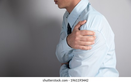 A Man Has A Shoulder Ache On A Gray Background