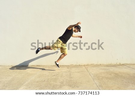 Man with a hat about to fall after stumbled in the sidewalk