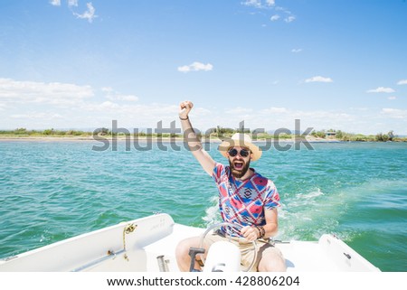 Man with hat, beard and sunglasses driving a boat and having fun on the blue sea in a sunny day.