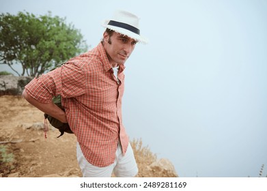 Man in a hat and checked shirt enjoying hiking in nature. Outdoor adventure and travel concept with serene and peaceful atmosphere. - Powered by Shutterstock